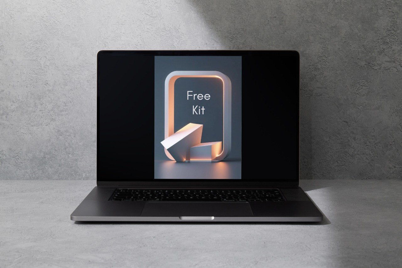 A dark gray laptop sits open on a light gray surface against a textured gray wall, with the screen displaying a graphic that reads 'Frame Set'.