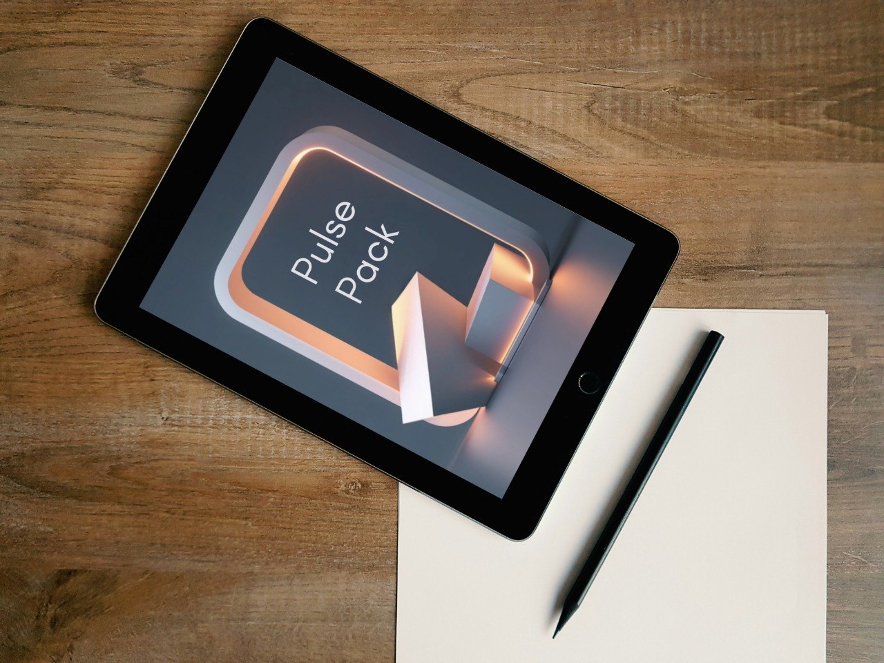 A tablet lying on a wooden desk, displaying a digital cover that reads 'Pulse Pack.' A blank sheet of paper and a stylus are placed beside it.